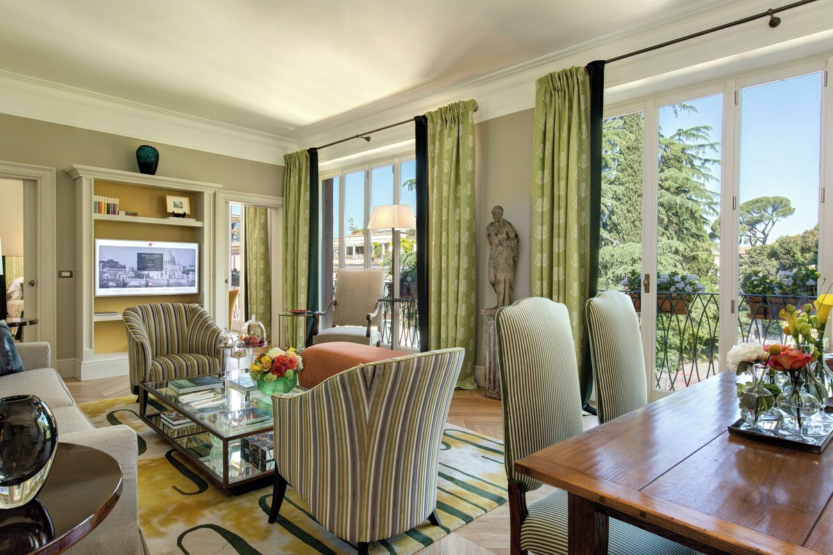 Un salón amplio con un ventanal grande, televisor y un comedor con mesa y sillas de madera.