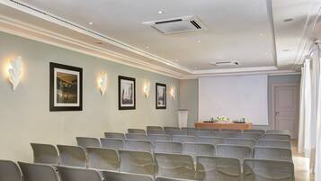 A conference room with rows of chairs, a podium, and framed pictures on the wall.