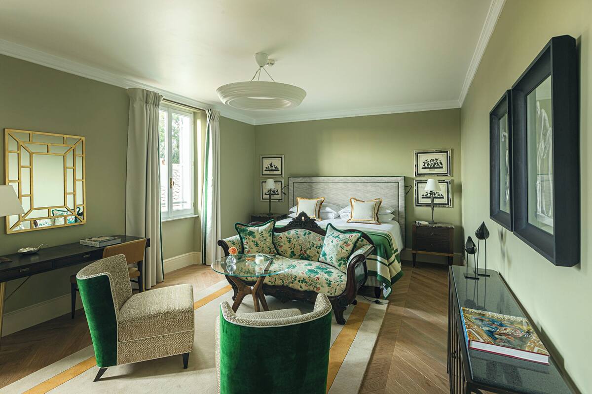 A well-lit bedroom with a bed, a desk, a chair, and a sofa.