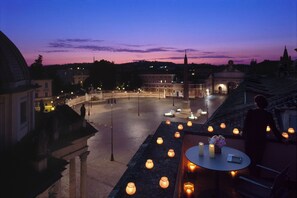 A terrace with candles, a table, and a view of a cityscape at dusk.