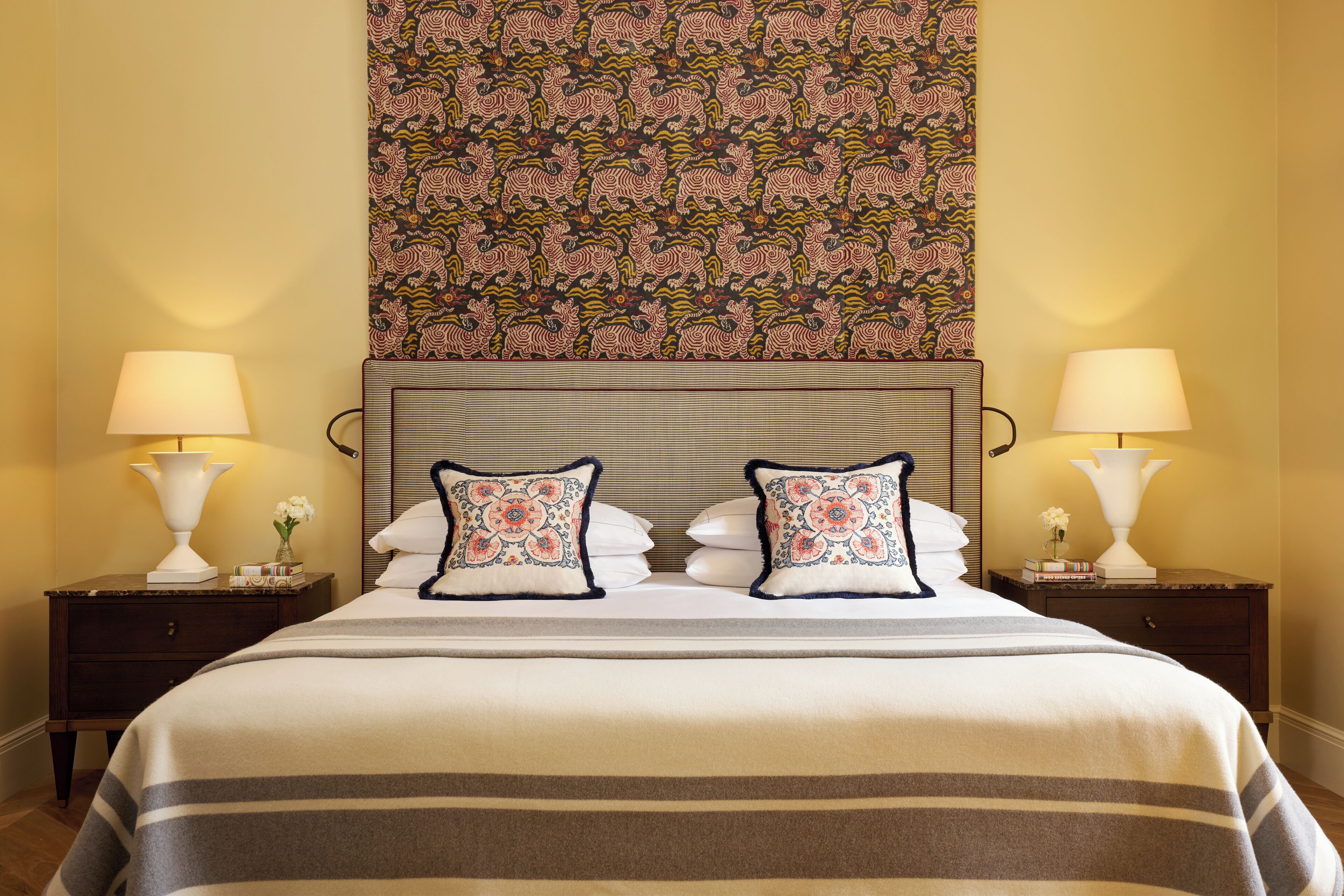 A hotel room with a large bed, two nightstands, and a patterned tapestry above the bed.
