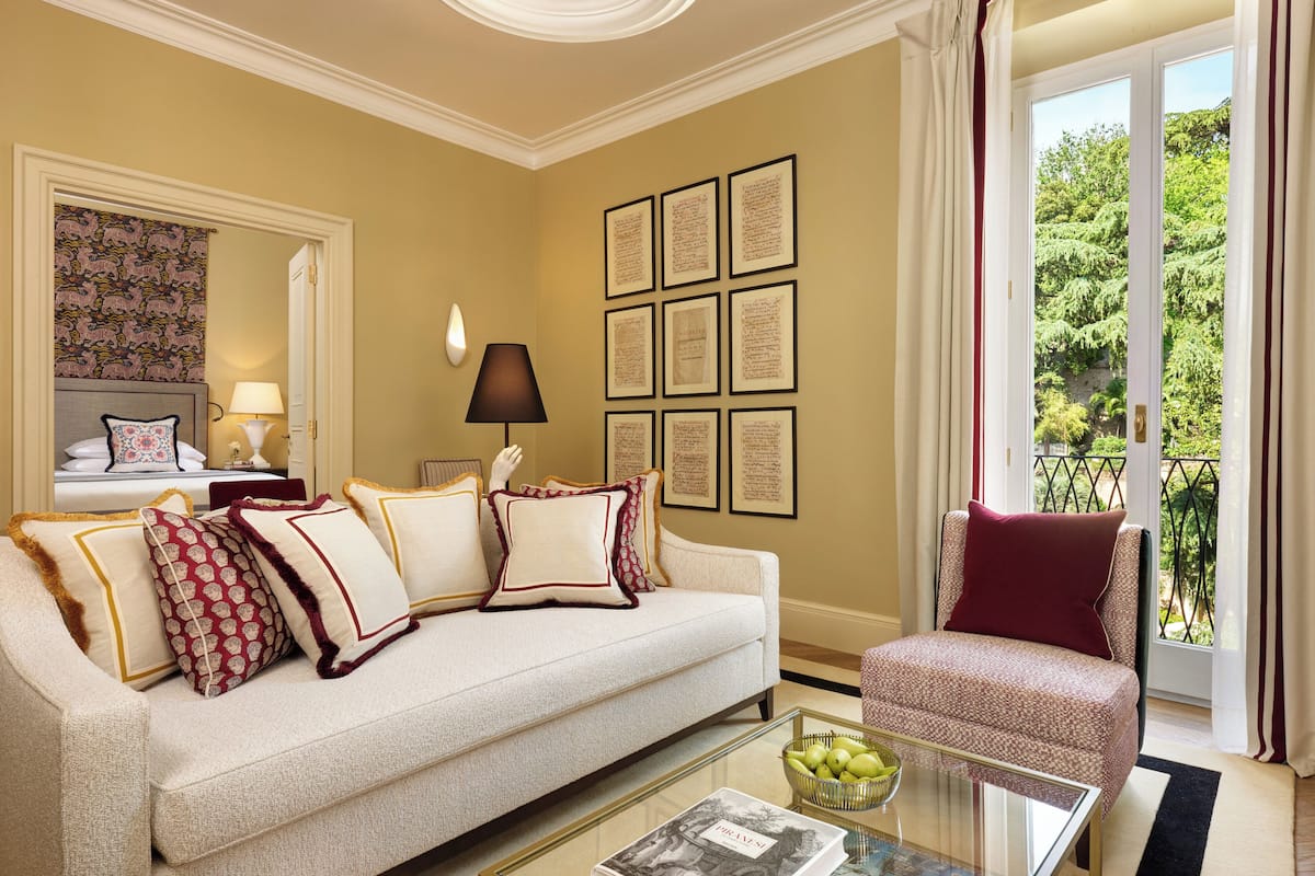 A well-appointed living room with a sofa, armchairs, a coffee table, and framed documents on the wall.