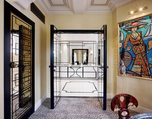 A modern interior with a geometric door design, a reflective mirror, and a vibrant abstract painting on the wall. - The Milestone Hotel (London)
