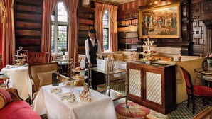 Una biblioteca con estanterías, un comedor con mesas dispuestas para una ceremonia de té y un cuadro en la pared.