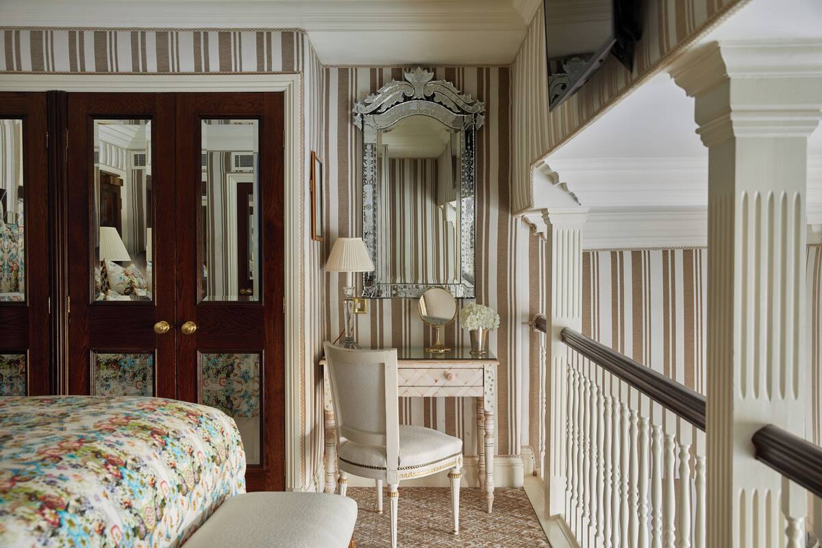 A bedroom with a bed, a dresser, a chair, and a mirror.