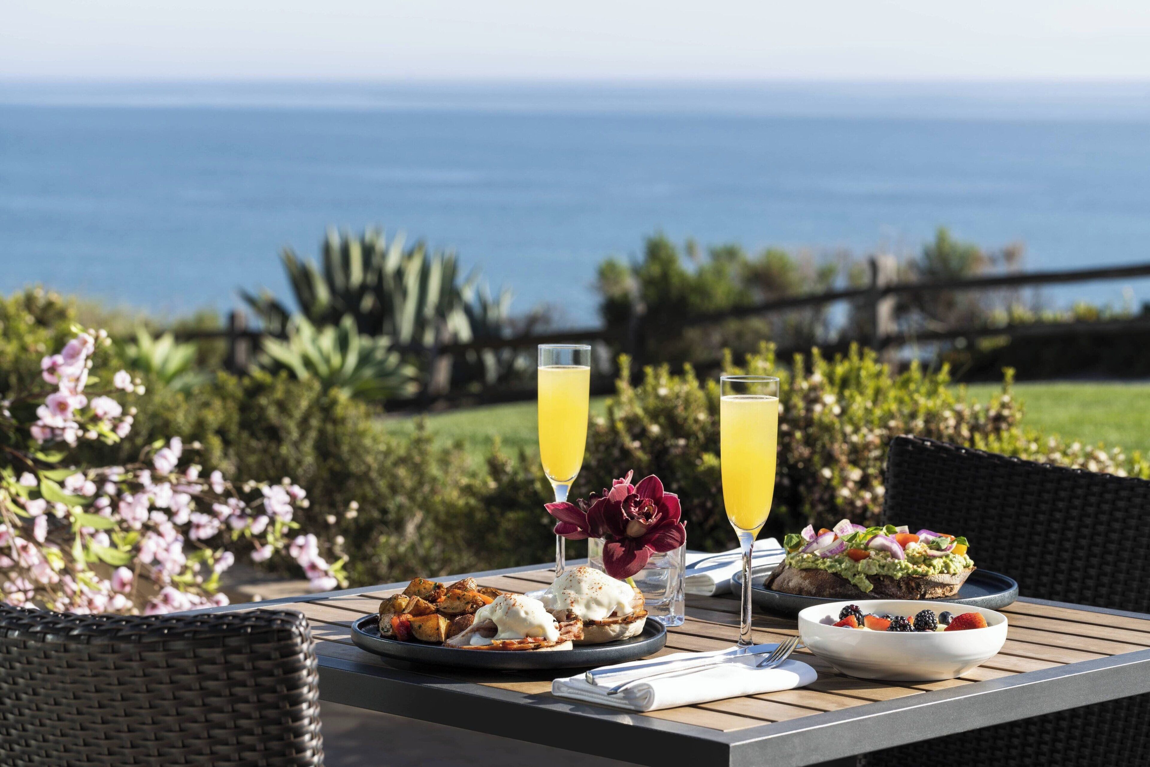 A table set with food and drinks, overlooking a scenic view.