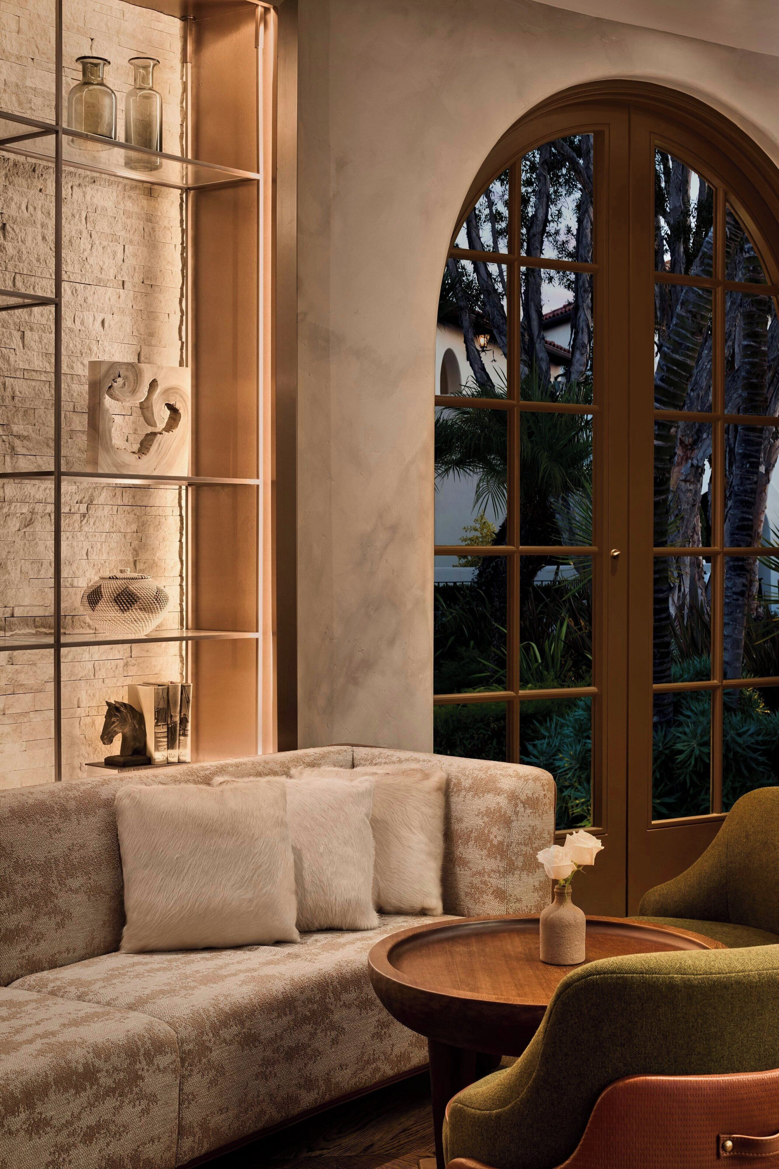 Ein gemütliches Wohnzimmer mit Backsteinwand, einem Holztisch, einem grünen Sessel und einer Couch mit Dekoration.