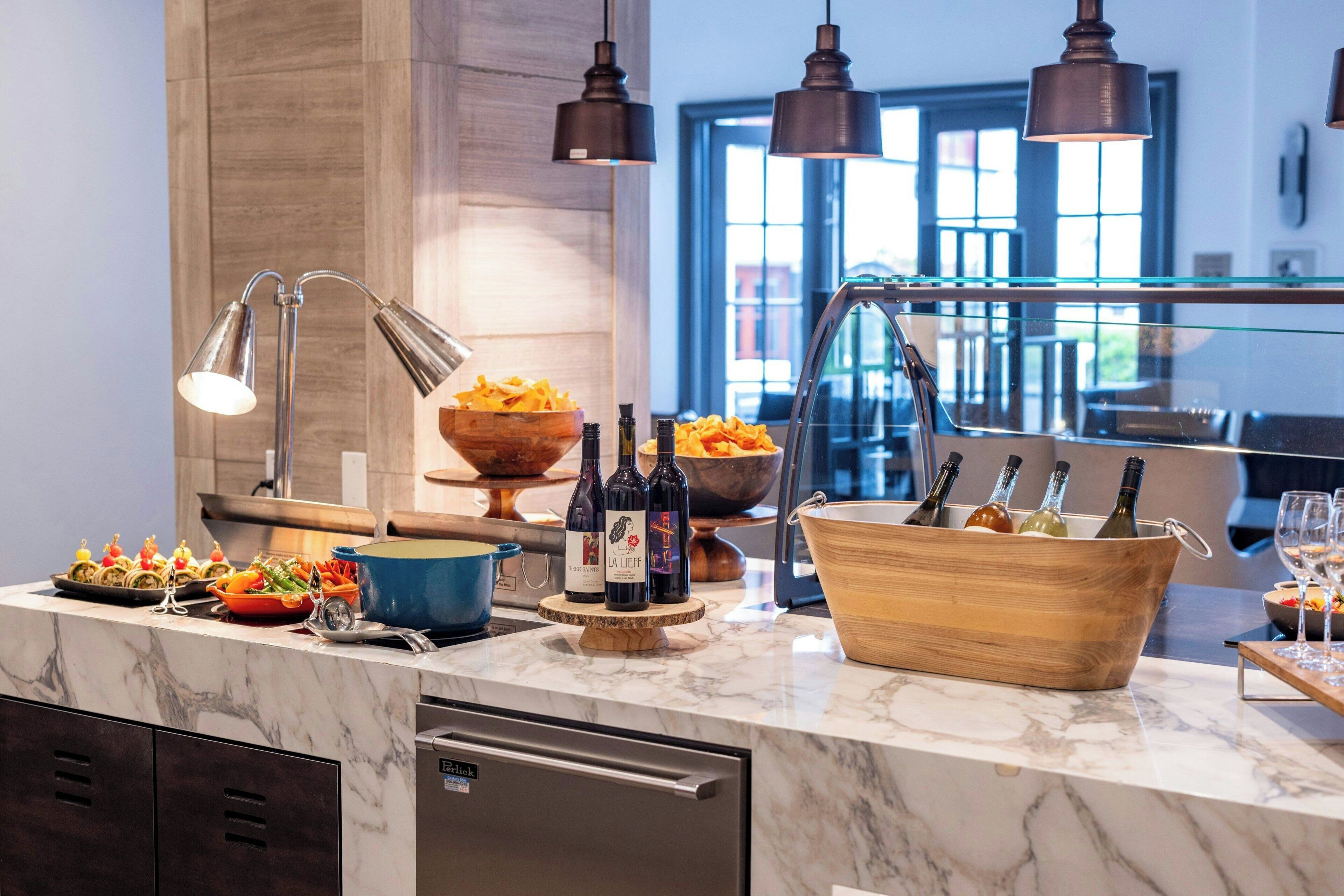 A modern kitchen with marble countertops, a built-in dishwasher, and a wine cooler.