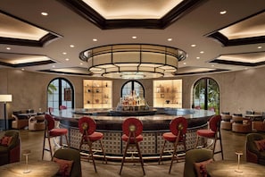 A spacious bar area with a central island, multiple seating options, and a modern ceiling design.