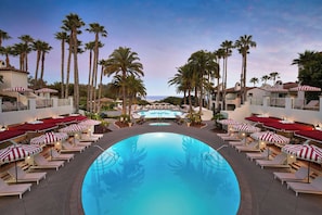 A pool area with lounge chairs and umbrellas, surrounded by palm trees and buildings. - The Ritz-Carlton Bacara, Santa Barbara (Goleta)