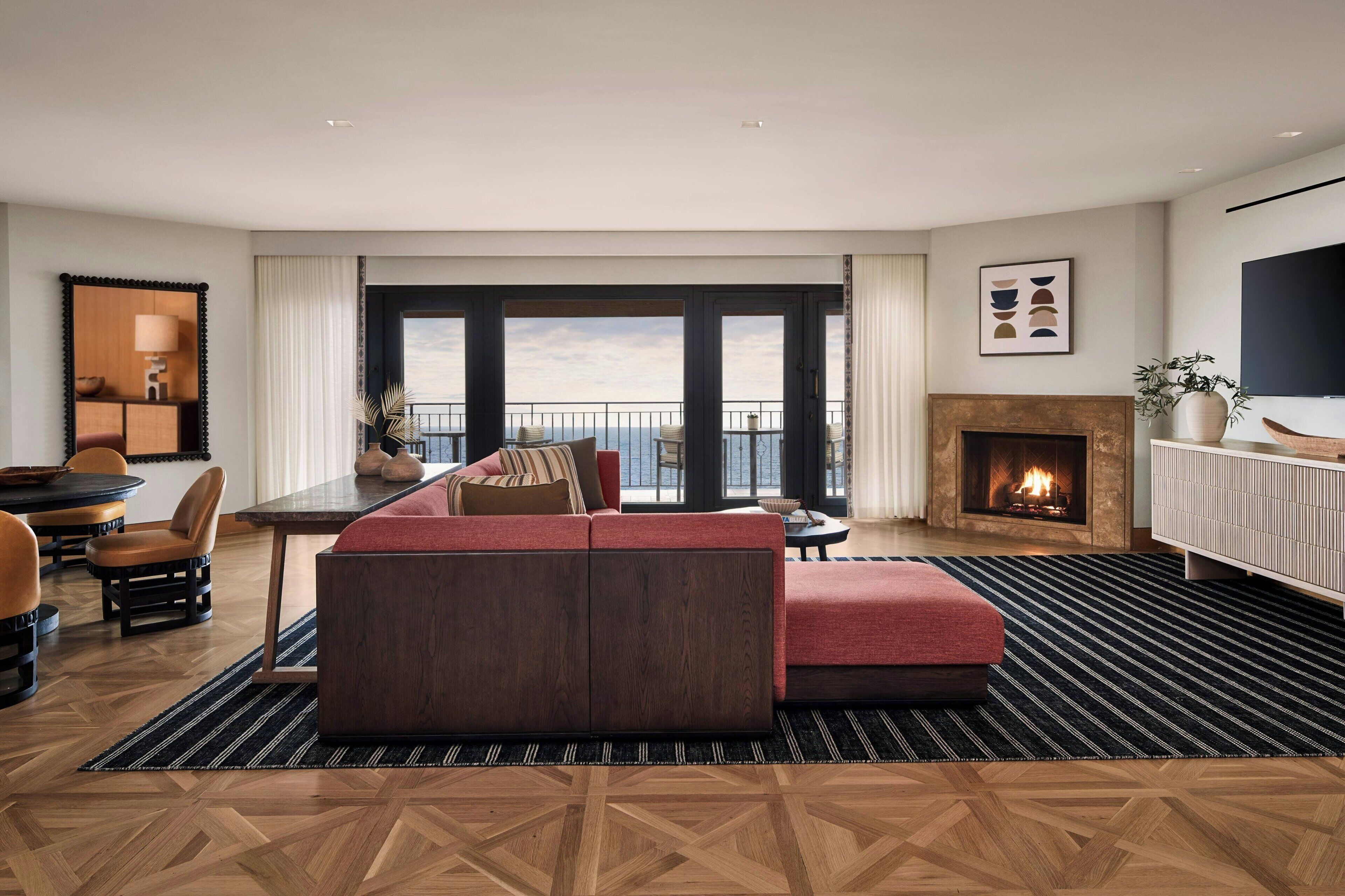 A modern living room with a sofa, a dining area, and a fireplace.