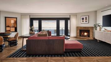 A modern living room with a sofa, a dining area, and a fireplace.