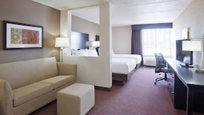 Habitación de hotel con sofá, escritorio, silla, cama y espejo.