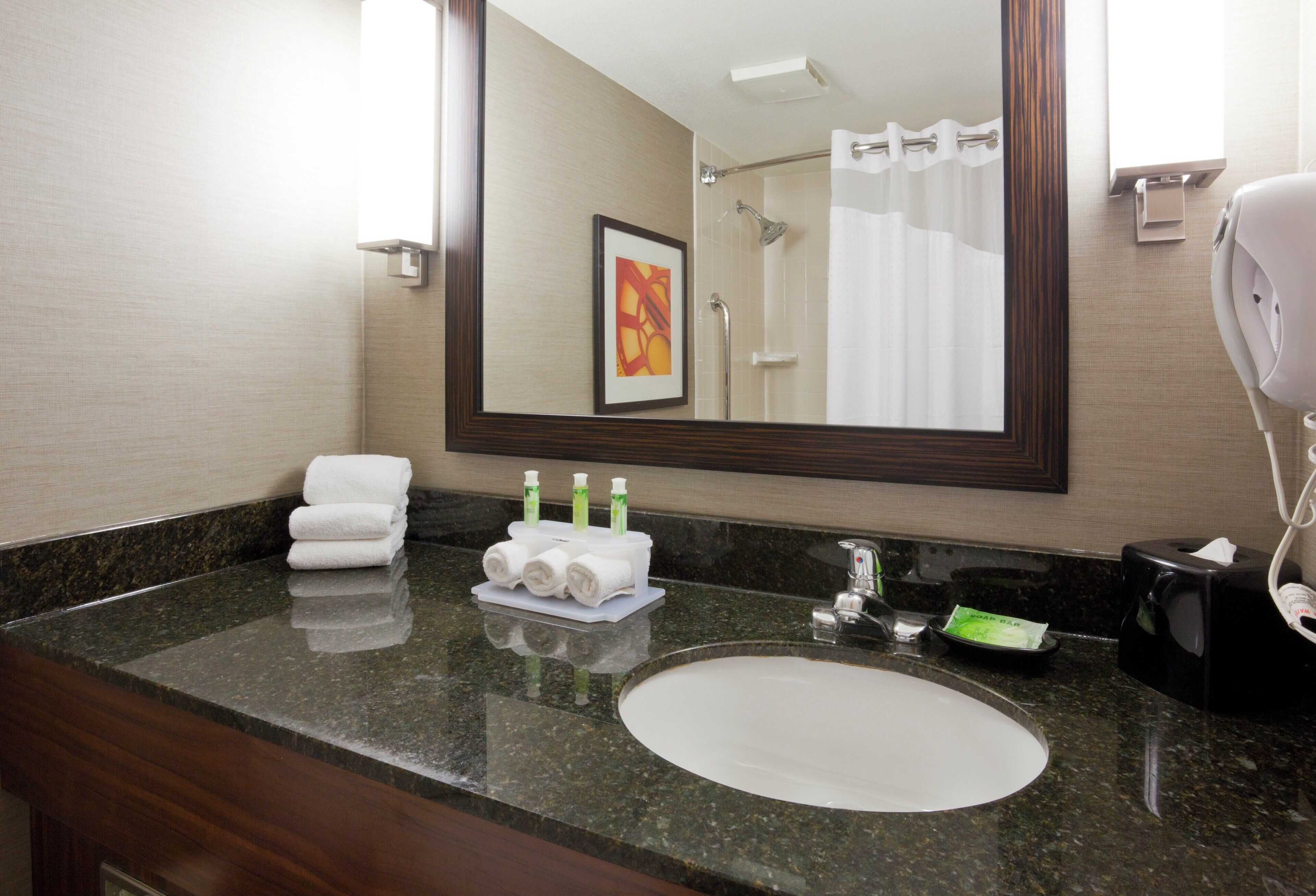 A bathroom with a sink, mirror, towel rack, and toiletries.