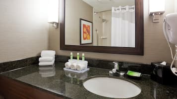 A bathroom with a sink, mirror, towel rack, and toiletries.