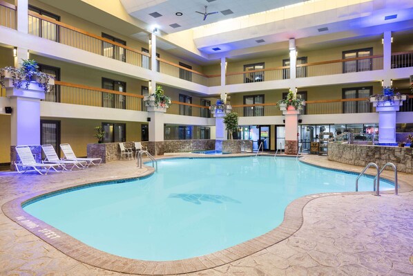 A multi-level indoor swimming pool with lounge chairs and potted plants.