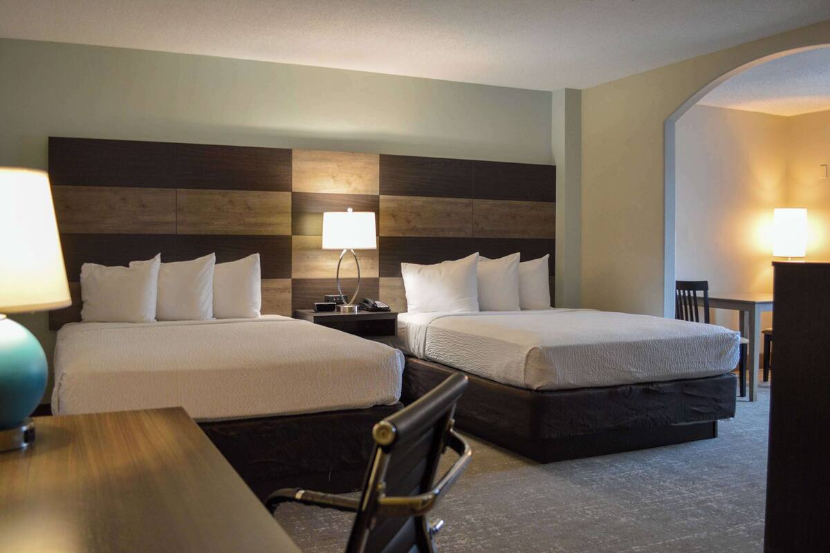 A hotel room with two beds, a desk, and a chair.