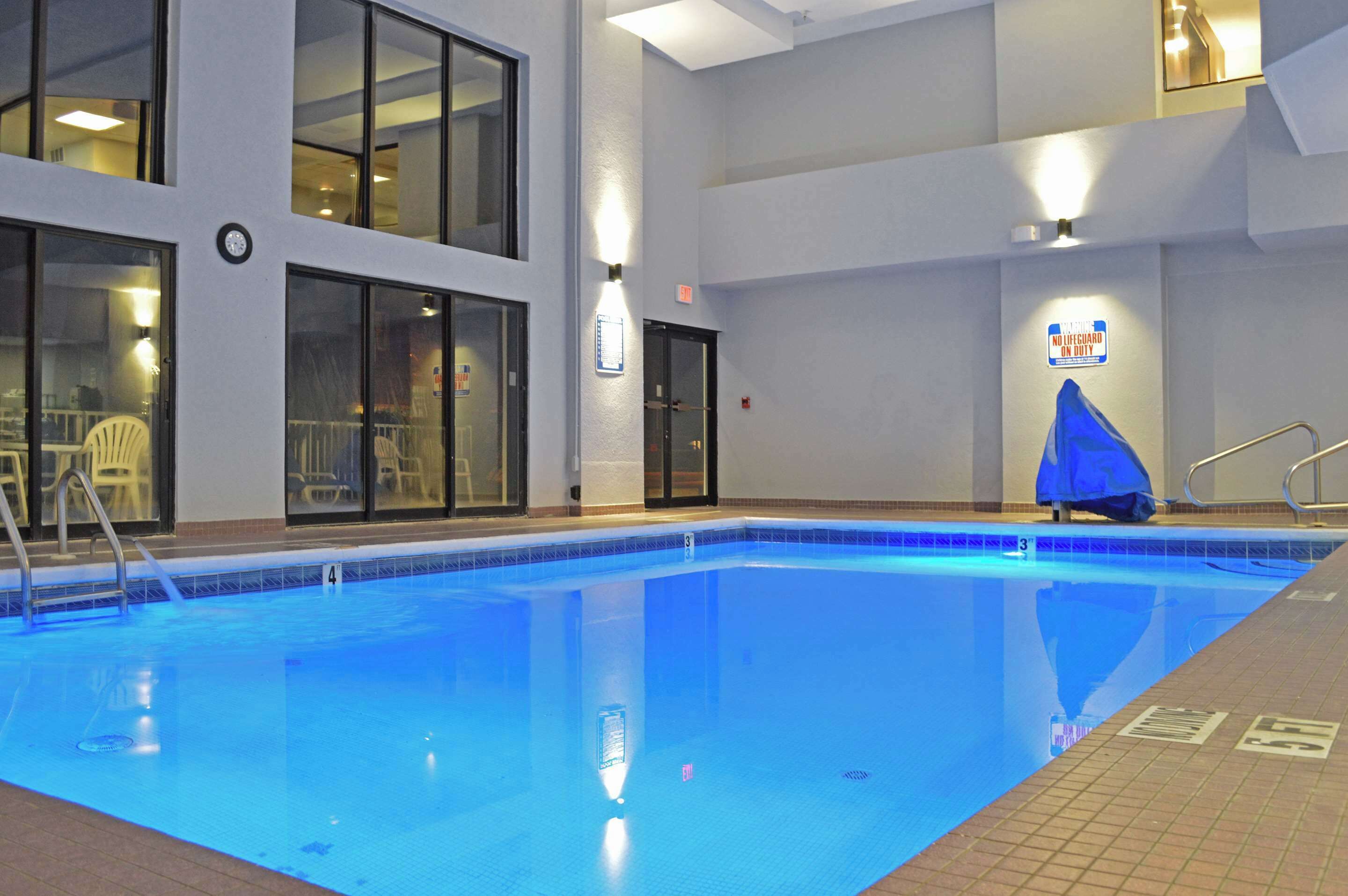 An indoor swimming pool with clear water, a lifeguard station, and a sign indicating no lifeguard on duty.