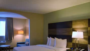 Une chambre d’hôtel comprenant un lit, un bureau, une chaise, une table de chevet et une lampe.