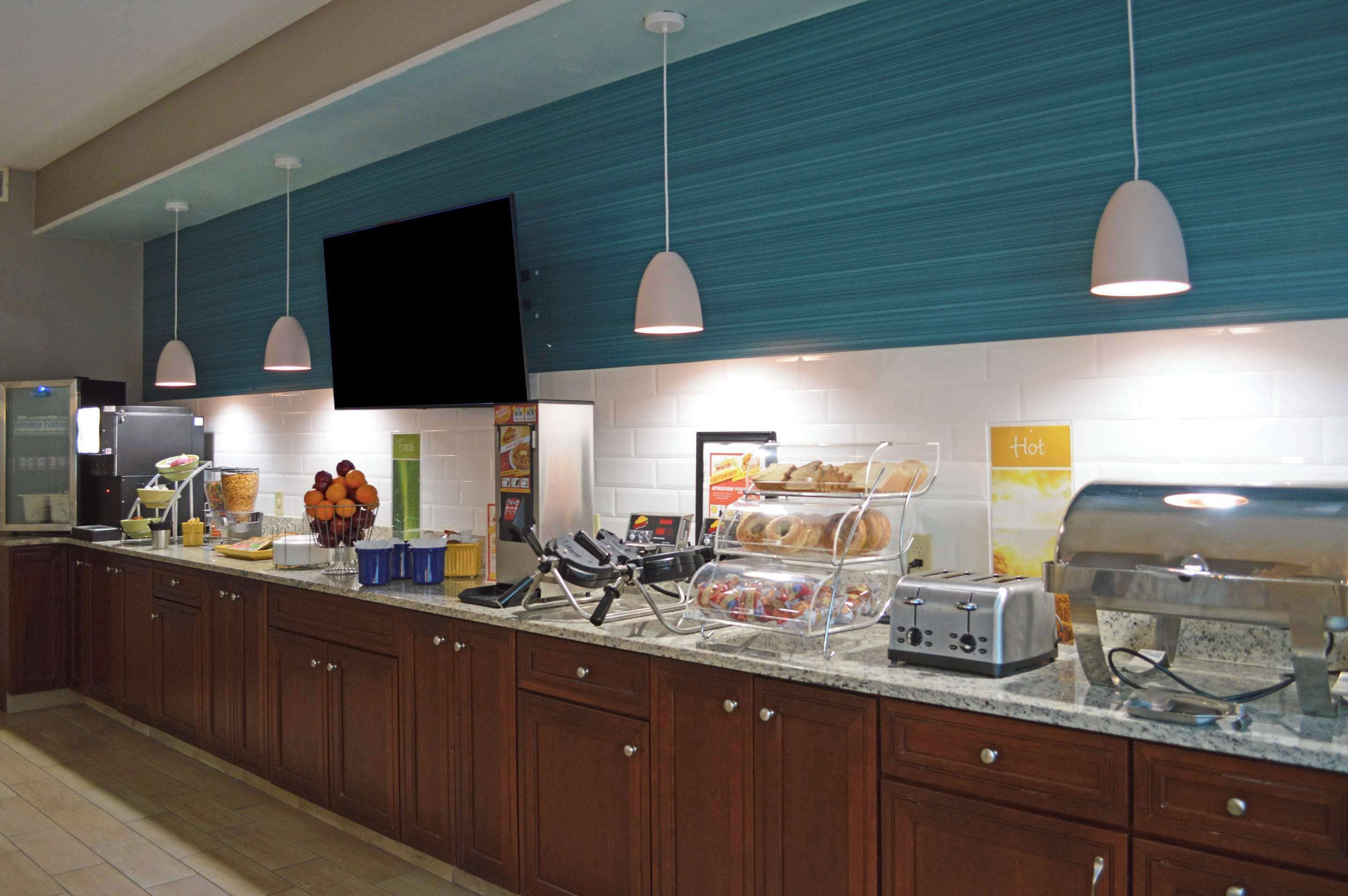 A hotel breakfast area with a self-serve station, toaster, and a sign indicating hot food.