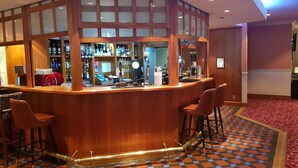 A bar area with a wooden counter, bar stools, and a checkered floor.