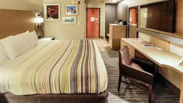 Una habitación de hotel con una cama grande, un escritorio, una silla, un televisor y una puerta.
