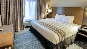 Une chambre d’hôtel avec un grand lit, un bureau, une table de chevet et une fenêtre avec des rideaux.