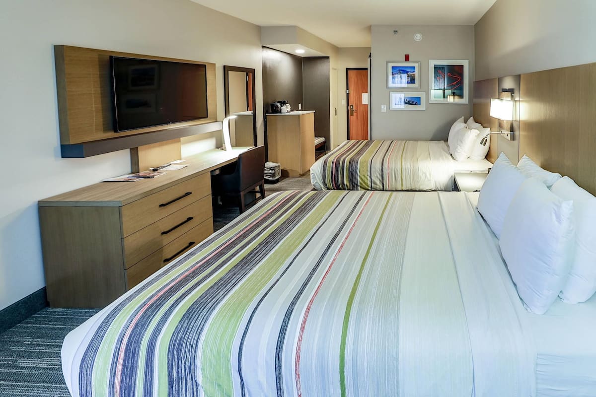 A hotel room with a large bed, a desk with a chair, a television, and a wardrobe.