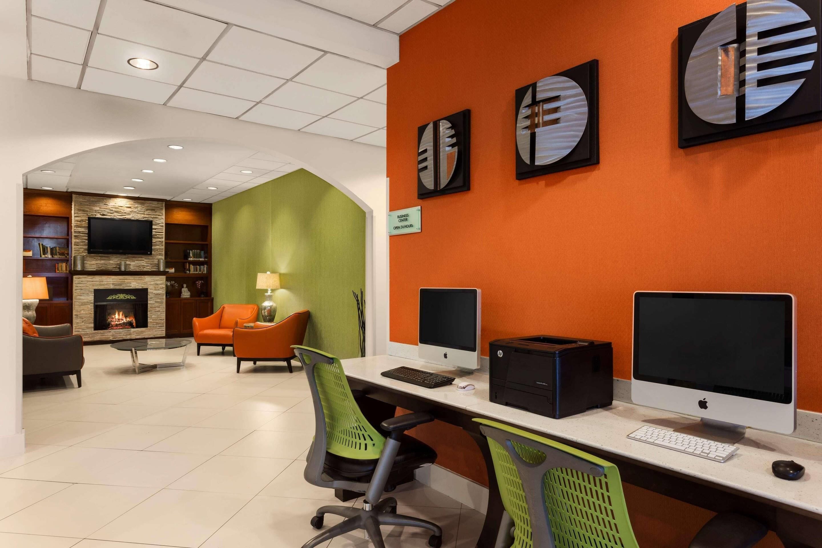 Un espacio de oficina moderno con dos escritorios, computadoras y una chimenea.