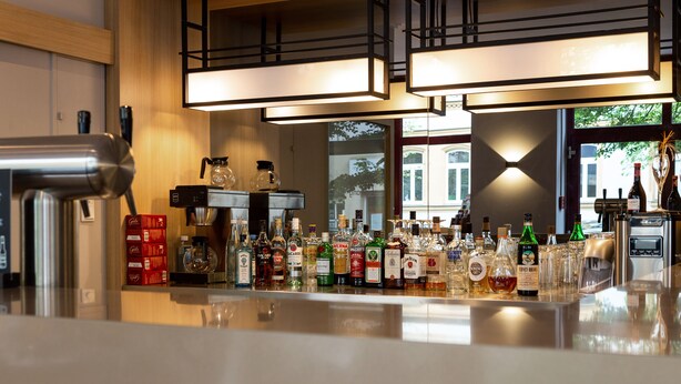 Een bar met verschillende drankflessen en een koffieapparaat.