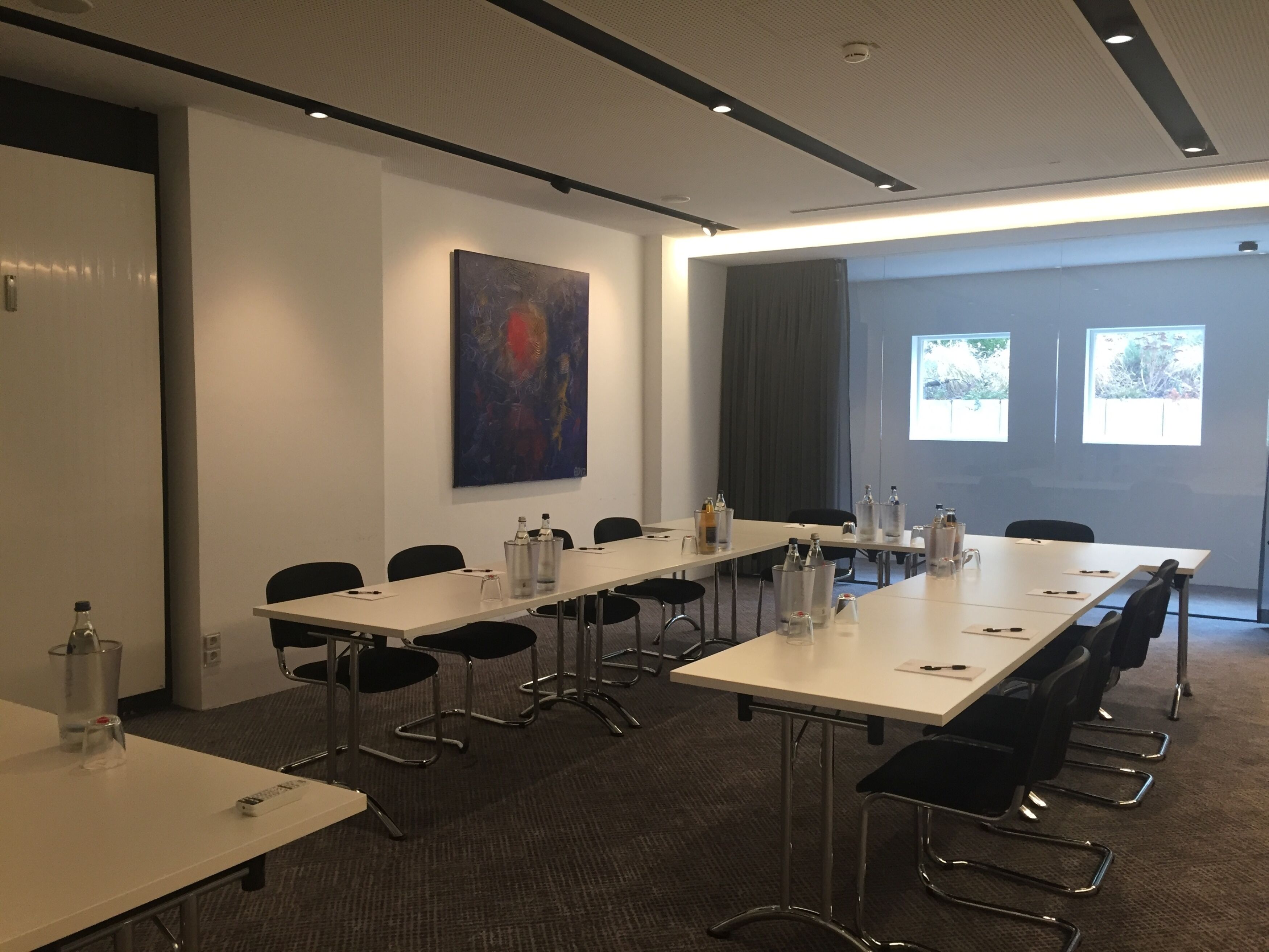 A conference room with a long table, chairs, and a projector screen.