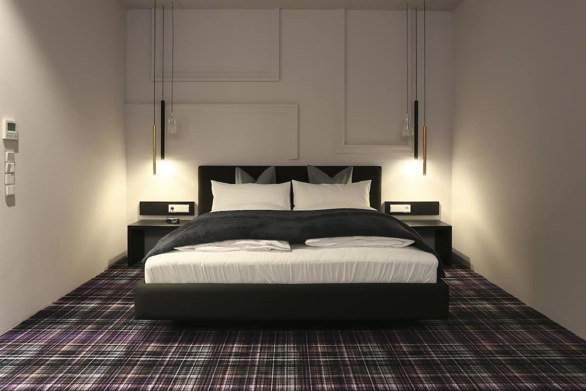 A modern bedroom with a large bed, two bedside tables, and pendant lighting.