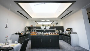 A modern kitchen with a central island, black cabinets, and a skylight. - Hotel Schempp (Bobingen)