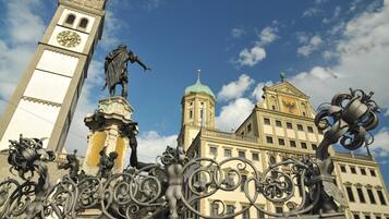 Un edificio storico con una torre dell'orologio, decorazioni in ferro battuto elaborate e statue.