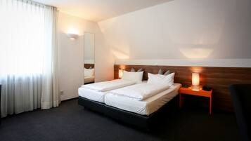 A hotel room with a double bed, bedside lamps, a nightstand, and a large mirror on the wall.