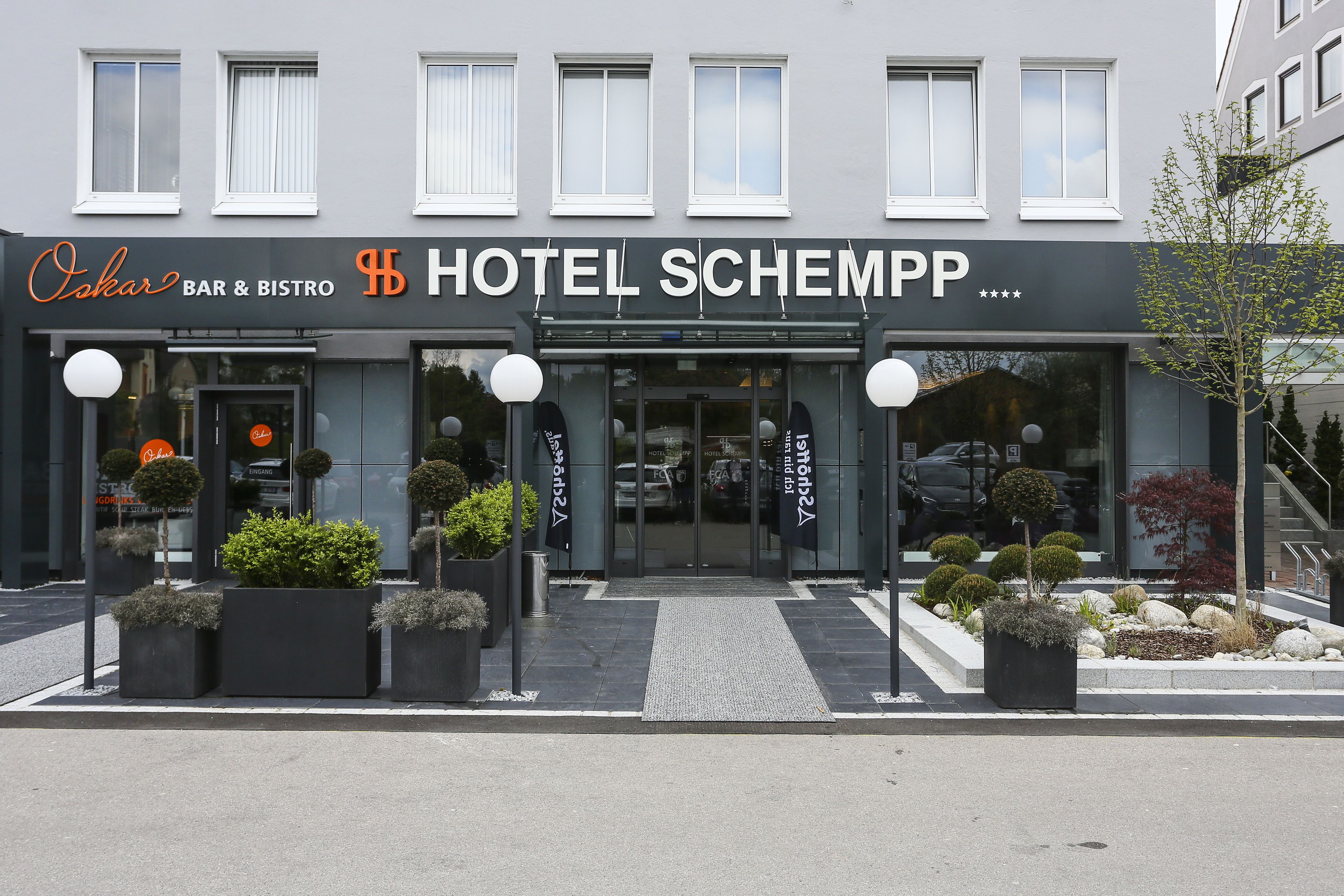 A hotel entrance with a bar and bistro named "Oskar" and "Hotel Schempf" signage.