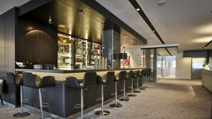 A modern bar area with a long counter and multiple bar stools. - Hotel Schempp (Bobingen)