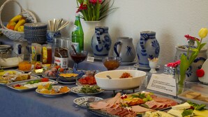 Een buffet met diverse soorten eten, bestek en decoratieve elementen zoals vazen en bloemen.