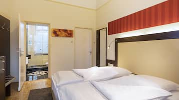 Ein Hotelzimmer mit Bett, Tür, Spiegel und einem Gemälde an der Wand.