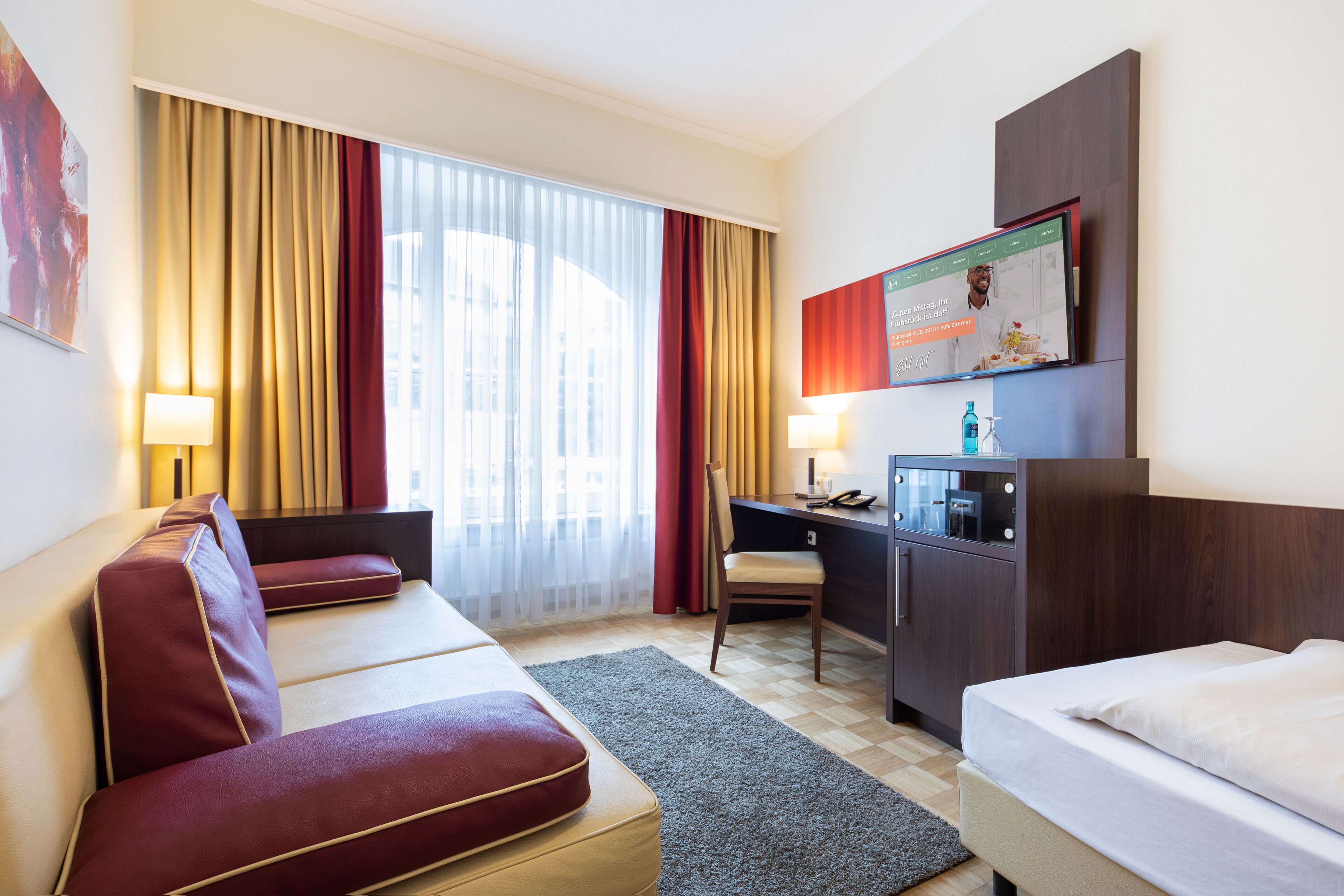 Una habitación de hotel con cama, escritorio, silla y sofá.