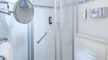 A modern bathroom with a glass-enclosed shower, a toilet, a sink, and a mirror.