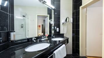 A modern bathroom with two sinks, a hairdryer, and a mirror.