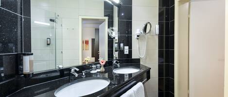 A modern bathroom with two sinks, a hairdryer, and a mirror.