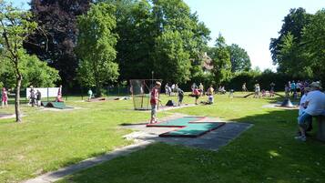 A park with green grass, trees, and people engaging in various activities.