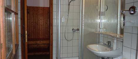 Un baño con ducha, lavamanos y espejo.