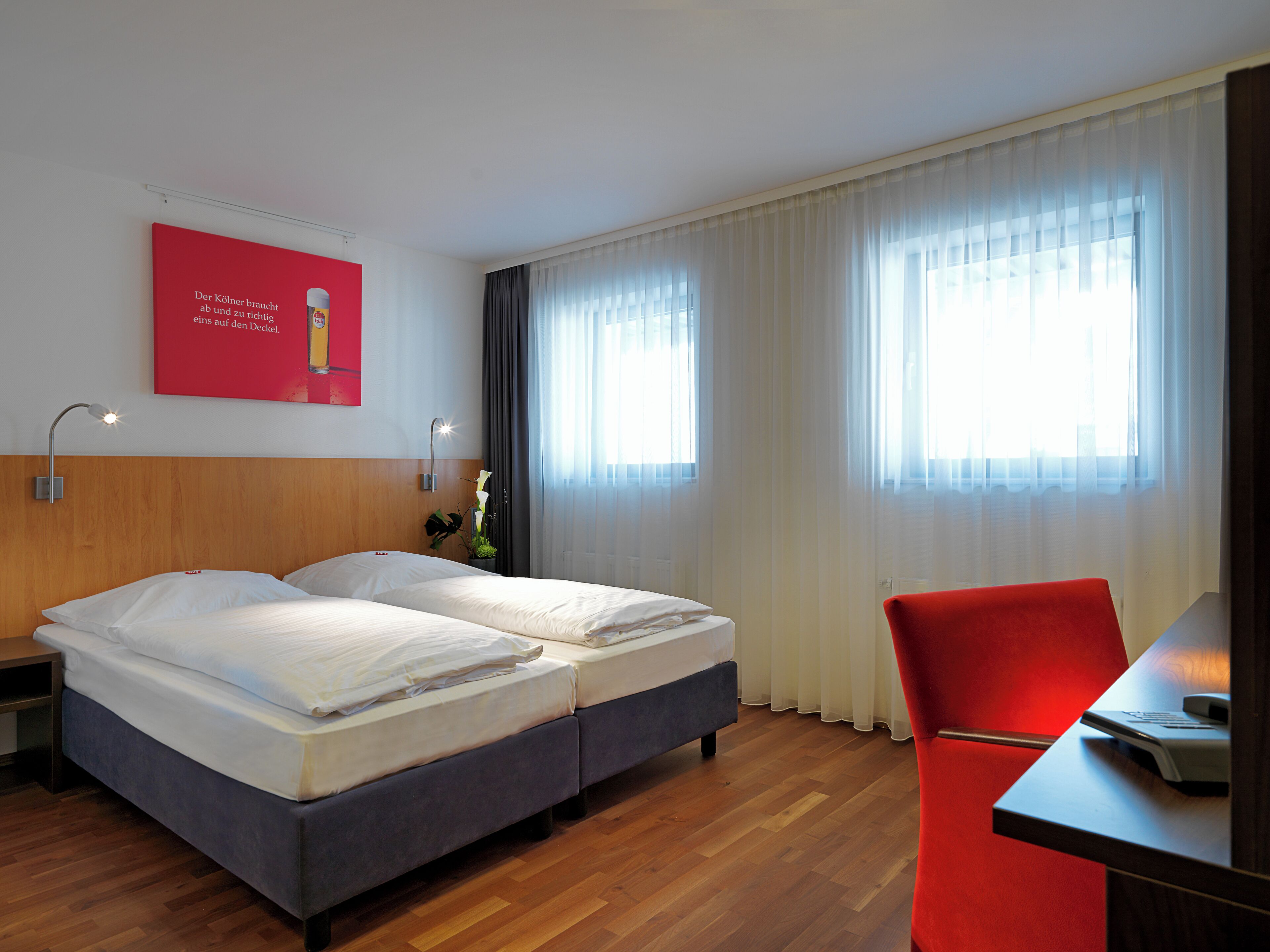 A hotel room with a bed, a desk, and a chair.