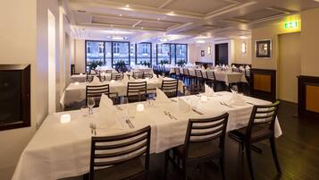 A restaurant with multiple round tables, each set with white tablecloths, chairs, and dining essentials.