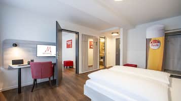 Habitació d'hotel amb un llit, escriptori, cadira i televisió.