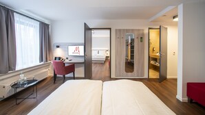 Une chambre d’hôtel comprenant un lit, un bureau avec un ordinateur, une chaise, un miroir et une armoire.