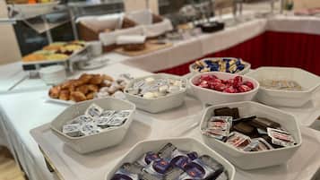 Ein Buffet mit verschiedenen Speisen, darunter Gebäck, Pralinen und verpackte Snacks.